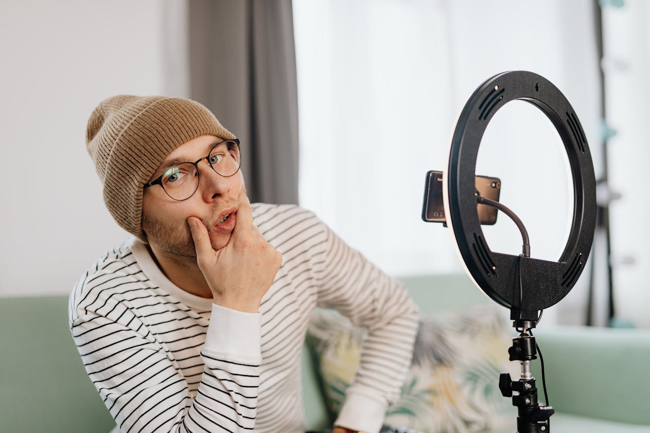 Crafting Captivating Headlines: Your awesome post title goes here Young content creator with beanie and glasses posing in front of ring light indoors.