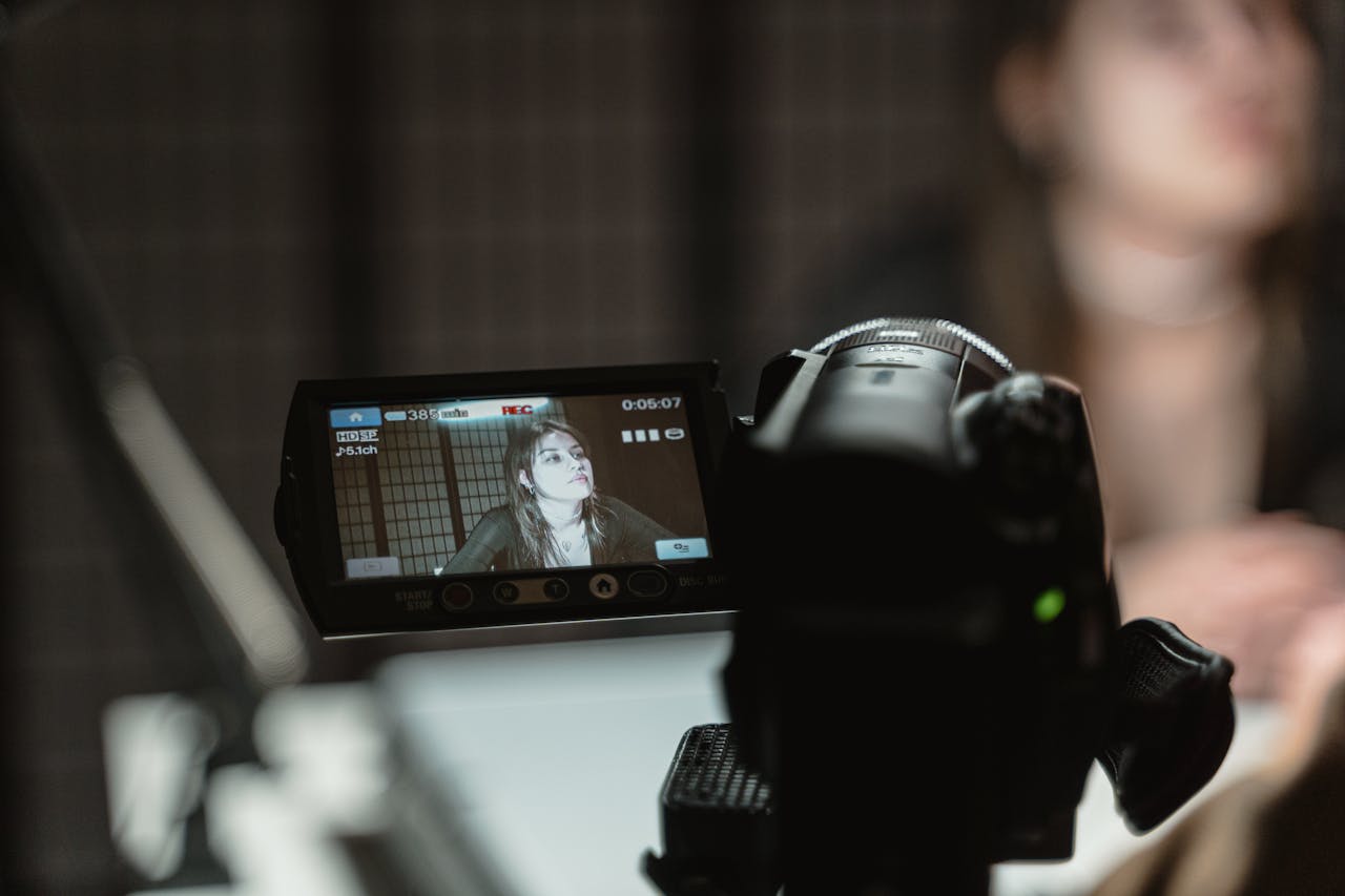 Close-up of a camera capturing a woman during a video shoot indoors.